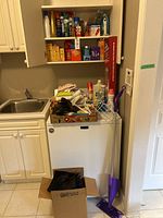 Photo showing cleaning supplies and mop stored near sink and cabinets with reusable bags in a box