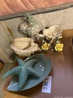 Glass leaf dish, turquoise starfish on shell dish, large ceramic shell dish, iridescent leaf bowl with serving spoons, rooster statue, and ceramic flower vases.