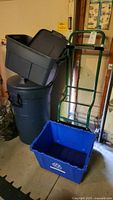 View showing Rubbermaid garbage can with lid, gray tote inside it, blue recycling tote in front, and green dolly standing behind totes