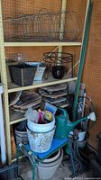 General view of gardening items showing tomato cages, planters, metal brackets, wooden pieces and garden stakes on shelves