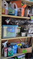 Shelves with assorted gardening supplies including large bottles of lawn seed, fertilizer, sprays, powders, and a box of pest control packets
