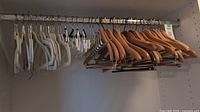 Wooden, pants, accessories and felt hangers on closet rod showing overall quantity and types.