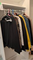 Jackets and pants hanging on closet rod showing variety of colors and styles