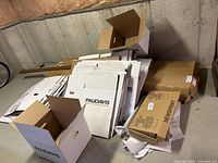 Photo showing a large pile of flat packed and a few assembled Paul Davis moving boxes along with packing paper and a brown box labeled Newsprint.