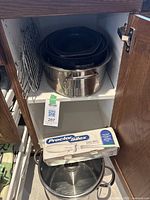 Photo showing enameled roasting pans nested in stainless steel pot, glass lid for pot, and boxed Proctor Silex Easy Slice electric cutting utensil.