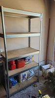 Full view of metal framed shelving unit filled with some items on lower shelves.