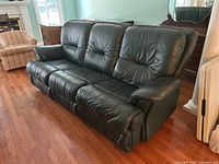 Front perspective view of the dark green leather sofa showing three tufted back cushions and overall form.