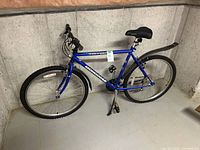 Side-angle photo of the blue Mongoose Threshold Sport men's bicycle showing the frame, tires with knobby tread, black fenders, and kickstand.