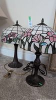 Two Tiffany style table lamps with floral stained glass shades positioned side-by-side showing front and side views.