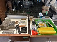 Drawer with multiple cooking utensils including graters, can opener, and other small kitchen tools