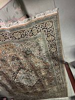 Partial view of the rug showing border pattern and fringe edge, with some wear visible.