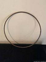 Full view of the round antique metal hoop against a beige wall to show overall size and condition.