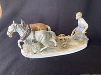 Side angle showing farmer holding plow with two horses in harnesses on oval base.