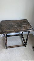 Full view of antique side table showing rectangular wooden plank top and turned legs with cross stretchers.