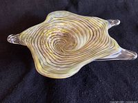 Top view showing the iridescent swirl pattern in yellow and brown tones on clear glass
