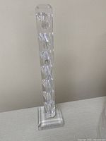 Front view of the clear plexiglass pipe rack showing seven circular pipe holder cutouts from the front, and the square stepped base.