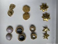All six pairs of vintage faux gold clip-on earrings laid out against a white background, showing different styles and designs.