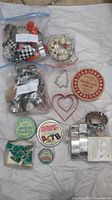 Overview photo of cookie cutters spread out along with several vintage cookie tins showing shapes and designs on cutters and tin lids.