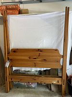 Full view of disassembled cherry wood bed frame components including posts, headboard, footboard, and side rails.