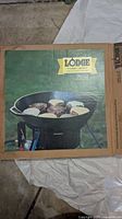 Photo of Lodge cast iron skillet packaging showing skillet cooking food on grill.