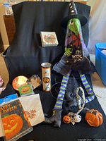 Full display of Halloween decorations including witch windsock, pumpkin, skull, napkins, plate, container, and string lights