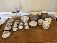 Full overview of entire Dansk Brown Mist stoneware set arranged on wooden table.