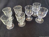 Seven Simon Pearce Essex goblets arranged on black background showing condition and size differences