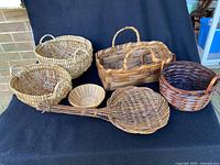 Full view of six assorted baskets showing different shapes and weaving styles on a black cloth background.