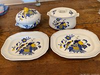 View of entire set: two casserole dishes with lids, two platters, all decorated with blue flowers, yellow fruit, and birds.