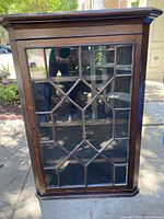 Front view showing glass paneled door with geometric wood muntin bars in a Victorian style corner cupboard.