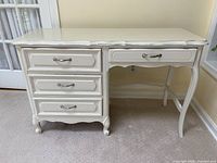 Front view of the vintage cream colored Henry Link desk showing three drawers on the left and one drawer on the right with metal handles.