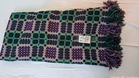 Folded purple and green wool blanket showing pattern and fringe