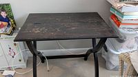 Wooden folding table showing dark stained surface with scratches and wear marks.