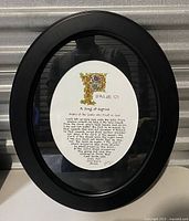 Frontal view of the black oval frame with the Psalm 121 print inside, showing the entire framed artwork with reflections on the glass.
