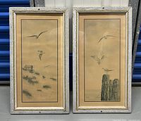 Both framed prints leaning against a wall, side by side showing their full views and frames with rope detailing.