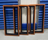 Four empty picture frames standing upright against a metal storage door