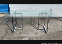 Front angle view showing the glass top and chrome metal base structure.