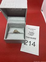 Ring presented in a gray jewelry box with auction lot number card