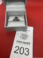 Ring displayed in gray presentation box on red background