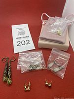 Overall lot on red background showing six pairs including plastic pouches and loose studs