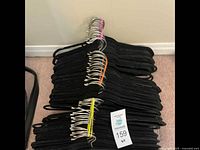 Multiple black velvet hangers stacked together showing silver metal hooks and velvet coating.