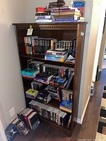 Photo showing the full wooden bookcase loaded with books and other items for scale.