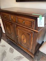 Front angle showing buffet cabinet with three drawers and two doors with inlaid wood design