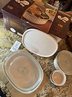 Photo showing original boxed set of CorningWare French White Baking Basics set with clear glass lids and white casseroles, and two white ramekins on countertop.