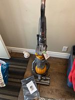 Front view of upright vacuum showing body, ball base, and attached hose and wand