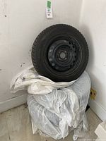 Four Falken Eurowinter winter tires mounted on black steel rims, stacked with visible tread and rims, against white wall background.