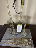 Overview of 2 wrought iron stands, 3 glass holders, and 8 glitter-filled glass taper candles on a table