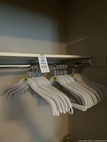 Grey velvet hangers arranged on a metal closet rod, showing multiple sets of hangers each labeled '20' on a small green tag.