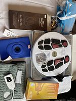 Photo showing EMS Foot Mat box, blue knee brace, instant heat pack box, control unit, and other health comfort items.