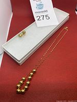Full view of necklace and earrings presented together in box on red background